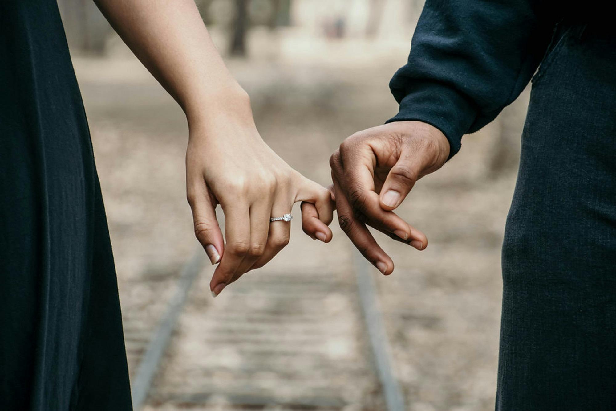 Close up of hands with 
			engagement ring
